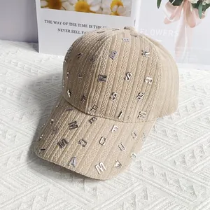 Dettaglio del berretto da baseball in velluto beige con rivetti a lettere argento