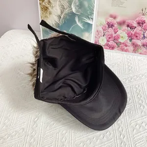 Detalle del forro interior y la peluca sintética larga de color marrón en la gorra negra