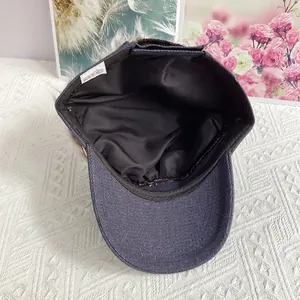 Detailed close-up of dark blue cotton denim cap interior showing white care label and lining