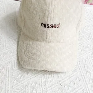 Detailaufnahme der cremefarbenen Fleece-Baseballkappe mit missed Buchstaben-Stickerei