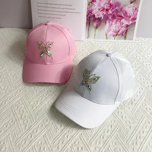 Detailed close-up of rhinestone butterfly embroidery on pink and white baseball caps