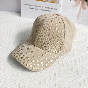 Close-up of beige corduroy baseball cap with golden rivets and striped texture detail