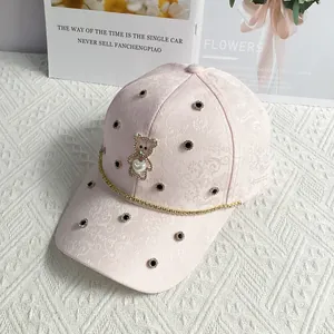 Detailed view of pink jacquard baseball cap with bear ornament and gold chain trim