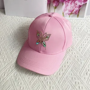 Detailed close-up of pink cotton baseball cap featuring a sparkling rhinestone butterfly