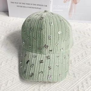 Dettaglio di un cappello da baseball in velluto verde chiaro con lettere metalliche argentate