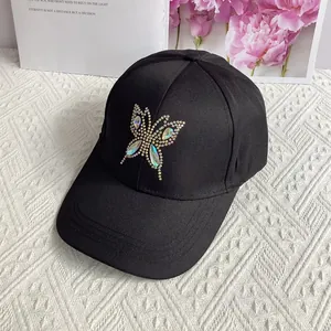 Close-up of sparkling rhinestone butterfly detail on black cotton baseball cap