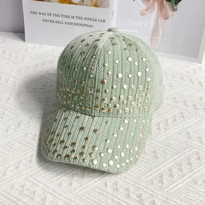 Detail of mint green corduroy baseball cap with decorative gold studs on white fabric