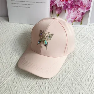 Close-up of pink baseball cap featuring a decorative rhinestone butterfly on the front