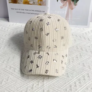 Dettaglio cappello da baseball in velluto a coste crema con lettere in metallo 3D