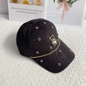 Close-up of black jacquard baseball cap with rhinestone bear and heart pearl detailing