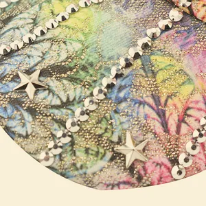 Detail of floral printed fabric with glitter finish, rhinestones, and star studs on cap