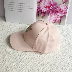 Detailed close-up of colorful rhinestone dragonfly embellishment on light pink baseball cap