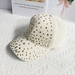 Detail of beige ribbed velvet baseball cap featuring gold metal stud decorations