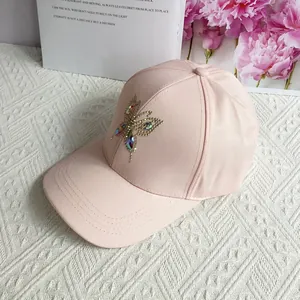 Detail of pink cotton baseball cap featuring sparkling rhinestone butterfly embellishments