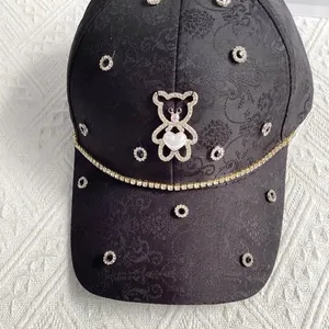 Close-up of black jacquard baseball cap with rhinestone bear and sparkling heart detail