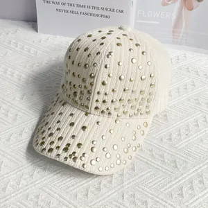 Detailed close-up of cream striped corduroy baseball cap with golden rivets decoration