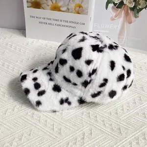 Close-up of soft plush cow print baseball cap on a textured knit surface with flowers