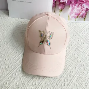 Detail of light pink baseball cap featuring a sparkling rhinestone butterfly design