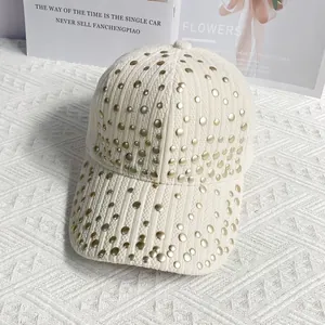 Detail of off-white corduroy baseball cap with gold rivet studs on white texture