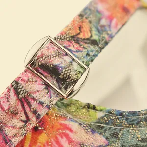 Close-up of floral print fabric with gold glitter and silver metal adjustment buckle