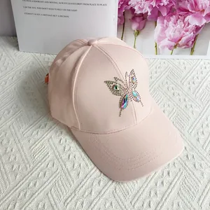 Detailed close-up of rhinestone butterfly decoration on a pink cotton baseball cap