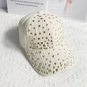Detail of off-white corduroy baseball cap with decorative gold round rivets on the visor