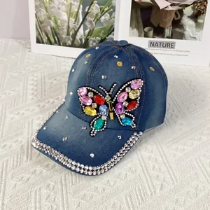 Detail of blue denim baseball cap featuring colorful rhinestone butterfly and studded brim