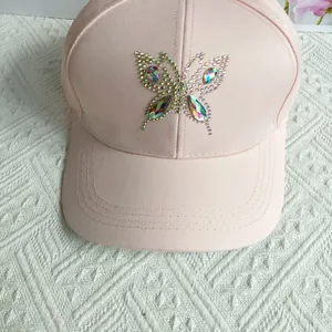Detailed view of pink baseball cap featuring sparkling rhinestone butterfly decoration