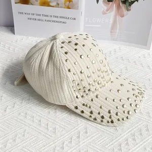 Detailed close-up of a beige corduroy baseball cap featuring trendy gold metal rivets