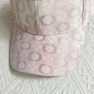 Dettaglio ravvicinato della delicata trama di pizzo floreale rosa e bianco sul berretto