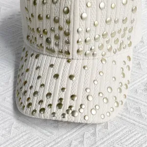 Close-up of beige velvet baseball cap featuring vertical stripes and gold metal rivets