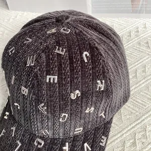 Dettaglio del cappello da baseball in velluto grigio scuro con lettere in metallo