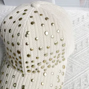 Detail view of cream corduroy baseball cap with vintage gold rivet decorations