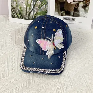 Detail of a washed blue denim baseball cap with sequin butterfly and rhinestone brim