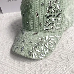 Close-up of light green corduroy baseball cap with sparkling rhinestone embellishments