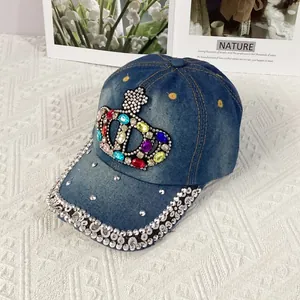 Detail of handcrafted crown baseball cap with colorful rhinestones on blue denim fabric