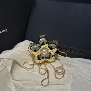 Golden flower metal clutch with oversized pearl detail and snake chain on gift box