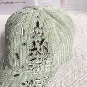 Detailed macro view of sparkling rhinestone clusters on green corduroy baseball cap