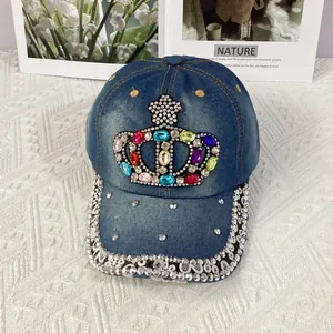 Detailed view of colorful rhinestone crown embellishment on dark blue denim baseball cap