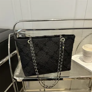 Fashionable black quilted tote bag with gold chain straps and sequins in a stylish setting