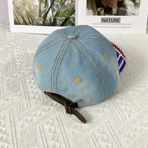 Detail of light blue denim cap featuring sparkling rhinestones on the brim and leather strap