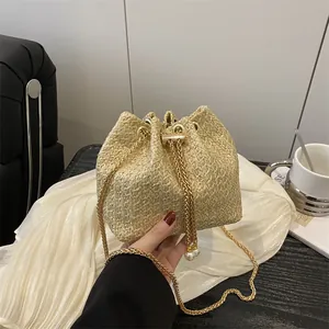 Sac seau chic en paille tressée beige avec bandoulière chaîne et charms en perles
