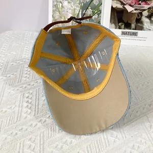 Detail of denim baseball cap interior showing 100% cotton tag and brown leather strap