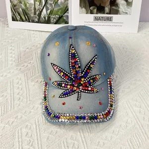 Detailed close-up of a blue denim baseball cap featuring colorful rhinestone maple leaf