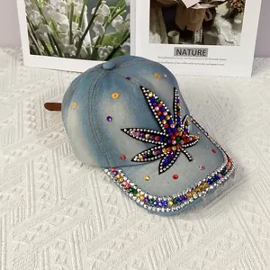 Close-up of light blue denim baseball cap featuring colorful rhinestone maple leaf design