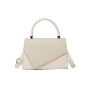 Minimalist beige crossbody bag with textured flap and gold metal trim in a 45-degree view