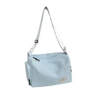 Sac bandoulière en toile bleu clair avec sangle réglable et poche latérale, vue latérale à 45°