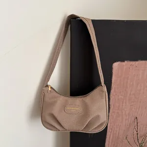 Borsa hobo marrone in tela con design a pieghe e tracolla larga appesa alla parete