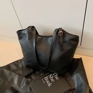 Retro black soft leather large tote bag with shoulder strap on a book background