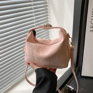 Borsa hobo rosa in finta pelle di serpente con dettagli dorati e luce naturale